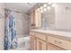 Bathroom featuring wood cabinets, a tile shower, and decorative blue shower curtain for added privacy and style at 18434 E Belleview Ln, Centennial, CO 80015