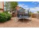 Backyard featuring a trampoline, flowering bushes, and mature trees surrounded by a wooden fence at 18434 E Belleview Ln, Centennial, CO 80015
