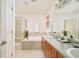 Bright bathroom featuring a soaking tub, glass-enclosed shower, and double vanity with stylish countertops at 1477 Serene Dr, Erie, CO 80516