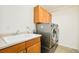 Laundry room with modern side-by-side washer and dryer units, and utility sink with storage cabinets at 1477 Serene Dr, Erie, CO 80516