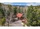 Aerial view of a cozy cabin with a detached garage surrounded by lush forest and mountain views at 9530 Aspen Ln, Conifer, CO 80433