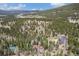 An aerial view of a charming home amidst a forest, mountains visible in the background at 9530 Aspen Ln, Conifer, CO 80433
