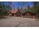 Charming cabin-style home with wood siding and a detached two-car garage nestled among trees at 9530 Aspen Ln, Conifer, CO 80433
