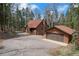 Exterior of a charming home with a detached garage, surrounded by lush trees and a winding driveway at 9530 Aspen Ln, Conifer, CO 80433