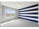 A spacious bedroom with a modern blue and white accent wall, large window, and neutral carpet at 12411 Irving Dr, Broomfield, CO 80020