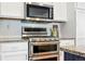 Modern kitchen featuring stainless steel appliances, white cabinetry, and tile backsplash at 12411 Irving Dr, Broomfield, CO 80020