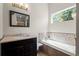 Bright bathroom features a soaking tub with tile surround, vanity, and a large mirror, with a peek into the glass shower at 1376 Banner Cir, Erie, CO 80516