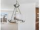 A modern chandelier lighting adjacent rooms with natural light streaming through an exterior sliding glass door at 9 Timberlake Ct, Byers, CO 80103