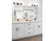 Bright bathroom featuring double vanity with quartz countertop and black hardware, plus large mirror and shower with glass door at 385 East St, Louisville, CO 80027