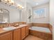 Bright bathroom featuring a large soaking tub, double sinks, and ample natural light from the window at 15496 W 66Th Dr # B, Arvada, CO 80007