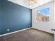 Bedroom with a blue accent wall, carpet, and a window looking at a neighboring house at 15496 W 66Th Dr # B, Arvada, CO 80007