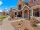 View of townhomes showcasing stone and siding exteriors, well-kept sidewalks, and manicured landscaping at 15496 W 66Th Dr # B, Arvada, CO 80007