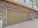 Attached garage door with tan finish and brick facade offers convenient parking at 15496 W 66Th Dr # B, Arvada, CO 80007