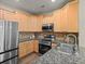 This kitchen showcases modern stainless steel appliances, granite countertops, and light wood cabinets at 15496 W 66Th Dr # B, Arvada, CO 80007