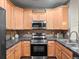 Well-equipped kitchen with wooden cabinetry, granite countertops, and stainless steel appliances offers a functional cooking space at 15496 W 66Th Dr # B, Arvada, CO 80007
