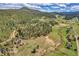 Beautiful aerial view of the property with a creek and trees surrounded by vast open spaces and mountain backdrop at 7753 Red Fox Dr, Evergreen, CO 80439