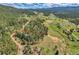 Aerial view outlining the property surrounded by lush greenery and rolling hills in the distance at 7753 Red Fox Dr, Evergreen, CO 80439