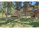 Expansive backyard with a wooden deck, surrounded by mature trees and lush greenery at 7753 Red Fox Dr, Evergreen, CO 80439