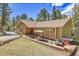 Charming single-story home with a brick-accented facade, inviting patio, and lush green landscaping at 7753 Red Fox Dr, Evergreen, CO 80439