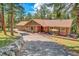 Charming single-story home with a brick-accented facade, inviting patio, and lush green landscaping at 7753 Red Fox Dr, Evergreen, CO 80439