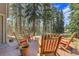 Enjoy the outdoors on this wooden deck surrounded by lush trees and comfortable seating for relaxation at 7753 Red Fox Dr, Evergreen, CO 80439