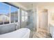 Bright bathroom featuring a soaking tub under a window and a glass-enclosed shower with modern fixtures and marble accents at 8300 Fairmount Dr # M103, Denver, CO 80247