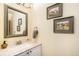Powder room featuring a white vanity with a marble countertop, a framed mirror, and charming country-themed wall art at 8300 Fairmount Dr # M103, Denver, CO 80247