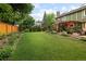 Lush backyard with vibrant green lawn, mature trees, a wooden fence, and a patio area for outdoor enjoyment at 1892 W Kettle Ave, Littleton, CO 80120