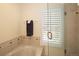 Bright bathroom featuring soaking tub with glass shower door, modern tiling, and a plantation shuttered window at 1892 W Kettle Ave, Littleton, CO 80120