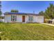 Exterior of home featuring a large lawn, white siding, an orange door, and solar panels on the roof at 10895 Fairfax Way, Thornton, CO 80233
