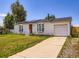 Exterior of home with white siding, a driveway, an orange front door, and solar panels on the roof at 10895 Fairfax Way, Thornton, CO 80233
