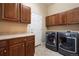 Laundry room with wooden cabinets and modern washer and dryer units at 744 Kryptonite Dr, Castle Rock, CO 80108