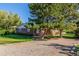 Charming brick home with mature trees and green lawn leading to a gravel driveway at 833 Applewood Dr, Lafayette, CO 80026