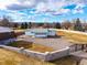 View of detached garage with white door and blue trim set in a large gravel yard with mountain backdrop at 833 Applewood Dr, Lafayette, CO 80026