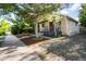 Single-story house featuring a front porch, landscaped yard, and a gravel driveway, offering a welcoming appeal at 4955 Julian St, Denver, CO 80221
