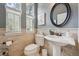 Charming half bathroom with pedestal sink, round mirror, and decorative wall accents at 7814 Inverness Blvd, Englewood, CO 80112
