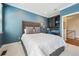Bedroom with a tufted headboard bed, blue walls, carpet flooring, and built-in desk and shelving at 7814 Inverness Blvd, Englewood, CO 80112