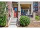 Inviting front entrance with a covered porch, red door with glass, and landscaped bushes at 7814 Inverness Blvd, Englewood, CO 80112
