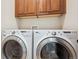 Laundry room with a front loading washing machine and front loading dryer under wooden cabinetry at 7814 Inverness Blvd, Englewood, CO 80112
