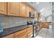 Well-lit kitchen featuring wooden cabinets, modern appliances, granite countertops, and a tiled backsplash at 7285 S Yukon Ct, Littleton, CO 80128