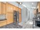 Spacious kitchen with wooden cabinets, stainless steel refrigerator, granite countertops, and tiled flooring at 7285 S Yukon Ct, Littleton, CO 80128