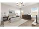 A bright bedroom with a ceiling fan, two windows, a bed and a decorative dresser at 8836 Waco Ct, Commerce City, CO 80022