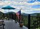Inviting deck with outdoor seating, blue umbrella, and an American flag, offering stunning views of the surrounding mountains at 83 Wilderness Cornerstone Rd, Evergreen, CO 80439