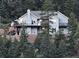 Charming gray two-story home nestled on a hill surrounded by lush trees and multiple decks at 83 Wilderness Cornerstone Rd, Evergreen, CO 80439