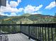 Deck with views of mountains and lush trees, beautiful blue skies with puffy clouds at 83 Wilderness Cornerstone Rd, Evergreen, CO 80439