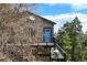 Gray two-story home with a blue door and black metal balcony, surrounded by trees at 8386 S Davco Dr, Morrison, CO 80465