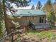 Charming home featuring gray siding, a green roof, and a small deck at 8386 S Davco Dr, Morrison, CO 80465