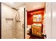 A full bathroom with stylish tile shower, wood vanity and red accent wall at 12632 W Virginia Ave, Lakewood, CO 80228