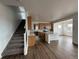 Open-concept kitchen boasts an island with a sink, hardwood floors, wooden cabinets, and seamlessly connects to the staircase at 7243 Prairie Sage Ln, Littleton, CO 80125