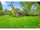 Expansive backyard with a well-manicured lawn, mature trees, and a charming covered patio at 7439 S Depew St, Littleton, CO 80128